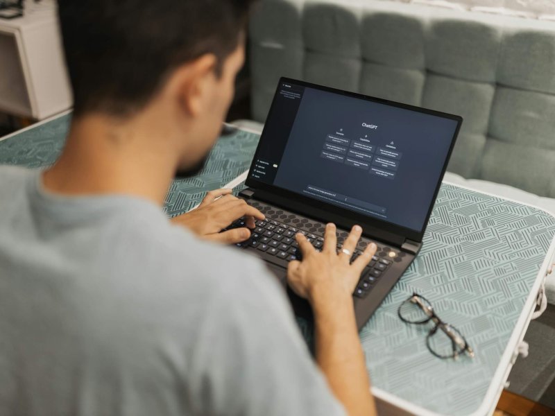 A man working on a laptop displaying ChatGPT's interface in an indoor setting.