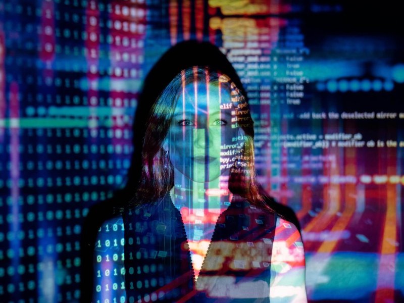 A woman with digital code projections on her face, representing technology and future concepts.